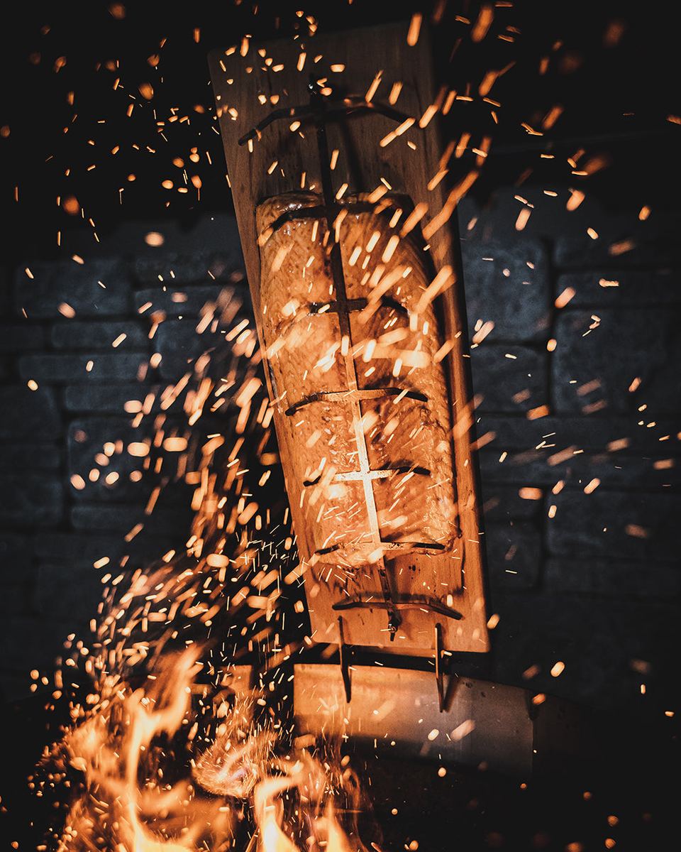 Ein Bargen Flammlachsbrett mit Lachsfilet an der Feuerschale, nachts im Funkenflug